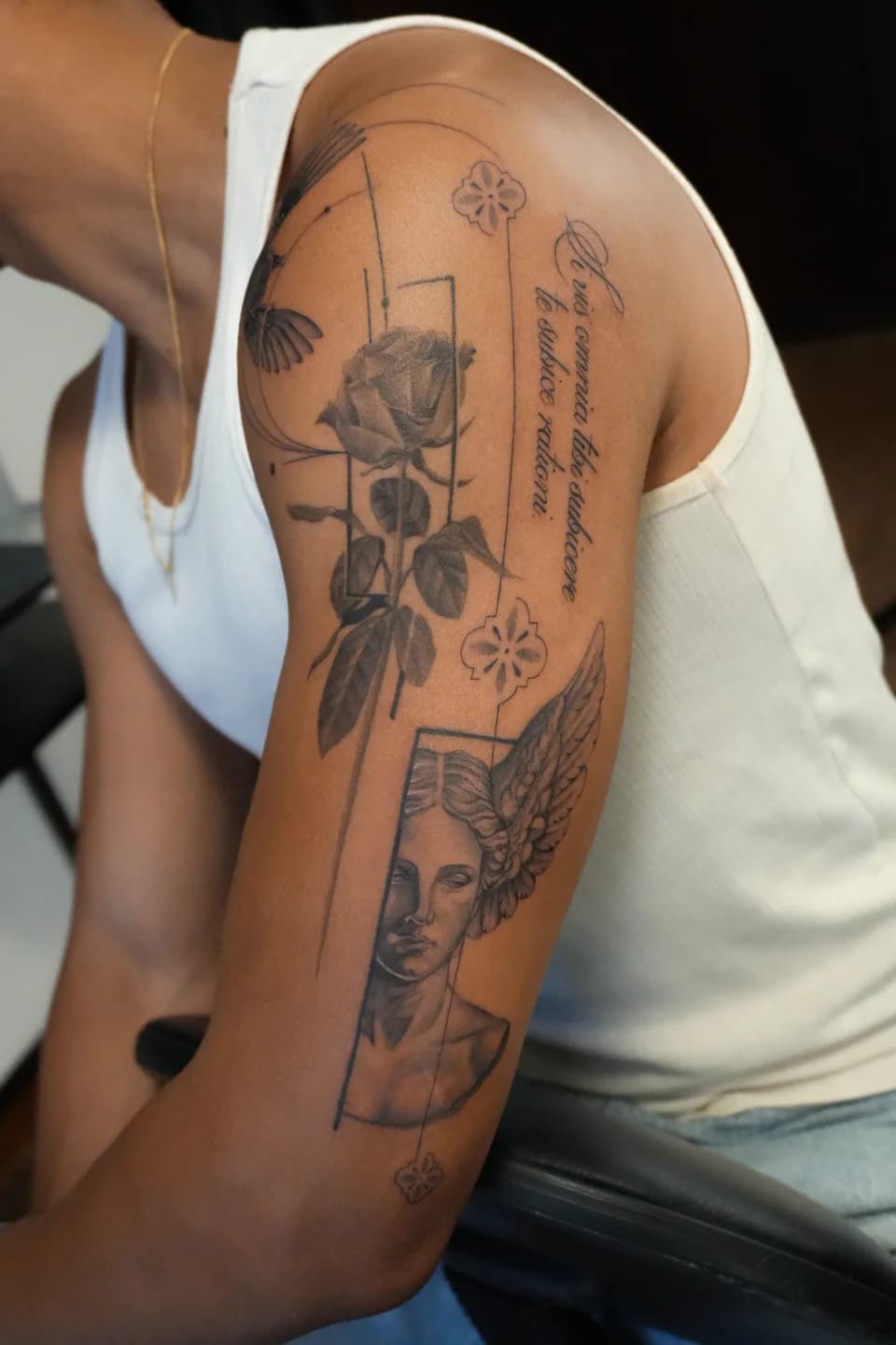 Composição de tatuagens no braço, com rosas, geometria e figura alada.